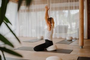 a woman sitting on a yoga mat in a room at Naturhotel Saalerwirt in San Lorenzo di Sebato