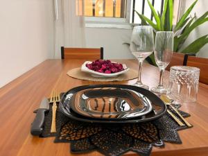 a wooden table with a plate of food and wine glasses at Le nid des Anges in Yaoundé