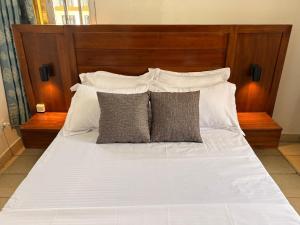 a large white bed with a wooden headboard and pillows at Le nid des Anges in Yaoundé