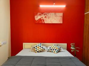 a bedroom with a red wall and a bed with two pillows at Hamsa Farmstay - 3BHK AC homestay in Mysore