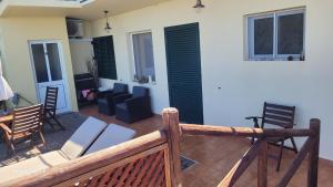 a balcony with chairs and a living room with black shutters at SUNSET REFUGE in Fajã da Ovelha