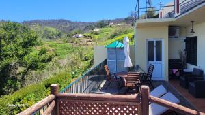 a balcony of a house with chairs and an umbrella at SUNSET REFUGE in Fajã da Ovelha