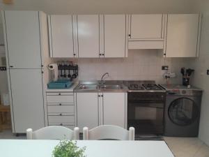a kitchen with white cabinets and a sink and a dishwasher at Vacanze da Paola in Campomarino +11 photos