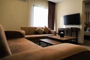 a living room with two couches and a tv at POST Hotel Amman in Amman