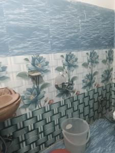 a bathroom with blue flowers on a tiled wall at Punchkedar in Phata