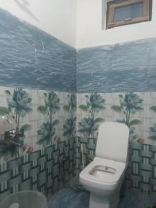 a bathroom with a toilet and flowers on the wall at Punchkedar in Phata
