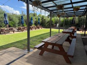 a row of wooden picnic tables under a canopy at Abermain Hotel in Abermain