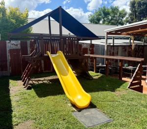 a yellow slide in a playground with a blue canopy at Abermain Hotel in Abermain