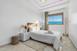 a white bedroom with a bed and a window at White Majorelle Horizon in Tamraght Ouzdar
