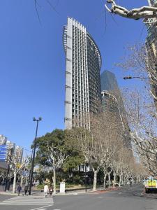 a tall building on a city street with trees at Shanghai Clivia Hotel in Shanghai
