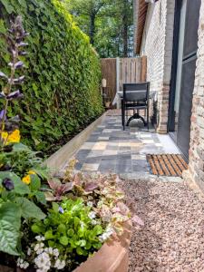a patio with a black chair and some plants at Aska Logies vakantiewoning in As