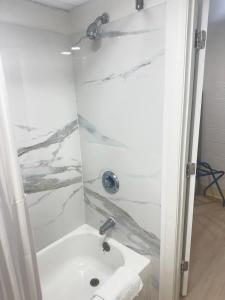 a white bathroom with a shower and a sink at Bourne Bridge Inn Former Eastern Inn in Bourne