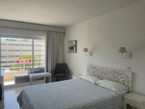 a bedroom with a bed and a window and a chair at Hostal Roberto in Palmanova