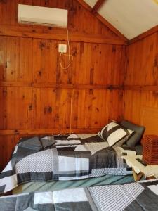 a bed in a room with wooden walls at Buffalo Street Cottages in Malelane +19 photos