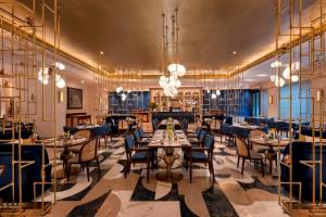 a restaurant with tables and chairs and chandeliers at The Park New Delhi in New Delhi