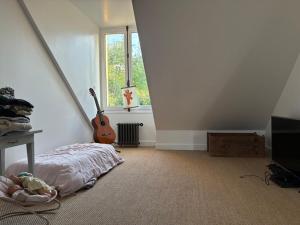 a bedroom with a bed and a guitar next to a window at Grande maison familiale rénovée en 2025 in Versailles