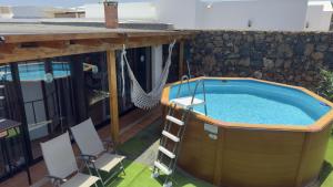 a hot tub on a patio with chairs and a hammock at Loft Tortuga in Tinajo