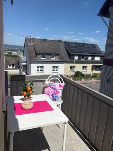 a white table on a balcony with flowers on it at Ferienwohnung Kirschtraum in Mülheim-Kärlich