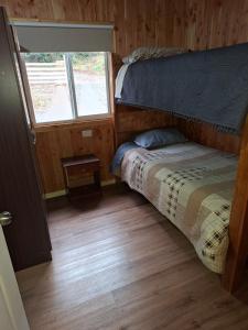 a small bedroom with a bed and a window at cabaña los ulmos in Lago Ranco