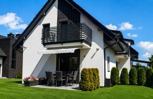 a white house with chairs and a balcony at Villa Luis in Dziwnów