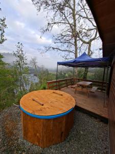 a wooden deck with a table and a blue tent at cabaña los ulmos in Lago Ranco
