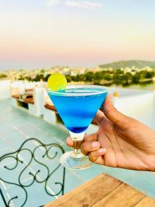 a person holding a blue drink with a lime on it at hotel sargam sadan in Jāmb
