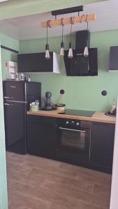 a kitchen with black cabinets and a stove and a refrigerator at Le cocoon de choupette in Cuvilly