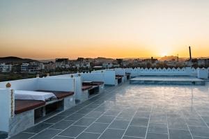 a rooftop with benches and a sunset in the background at hotel sargam sadan in Jāmb