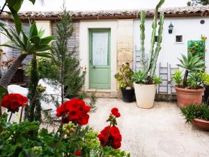a house with red flowers in front of a green door at A Lumia in Noto