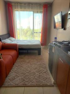a room with a couch and a bed and a window at Reinastays in Kiambu