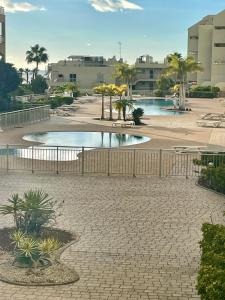 a pool in a courtyard with trees and buildings at casa kayla in Palm-Mar