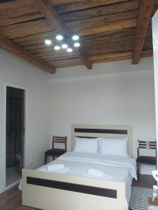 a bedroom with a white bed with a wooden ceiling at White House in Gyumri