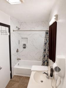 a white bathroom with a tub and a sink at Buffalo Inn Vintage MOTEL in Canyon