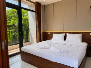 a bedroom with a bed with white sheets and a window at Lucky Hostel in Vientiane