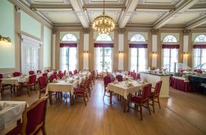 ein Esszimmer mit Tischen, Stühlen und einem Kronleuchter in der Unterkunft Grand Hotel Rogaska in Rogaška Slatina