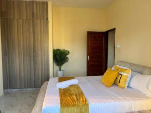 a bedroom with a large bed with yellow pillows at The Wink apartments in Malindi