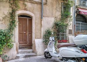 a scooter parked in front of a building with a door at 17m2 Flower studio dans le centre historique Ecusson in Montpellier