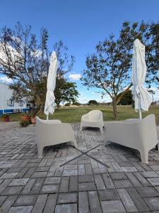 three white chairs and umbrellas on a patio at Retiro dos Batudes in Palmela