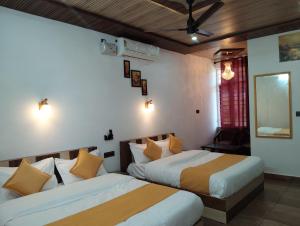 a bedroom with two beds and a mirror at Hotel Aqua Waterfall in Dharamshala