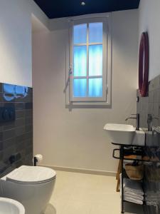 a bathroom with two sinks and a toilet and a window at La Locanda Azzurra in Sanremo