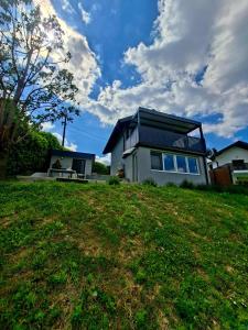 a house on top of a grassy hill with a sky at KUĆA za odmor 128 in Plešivica