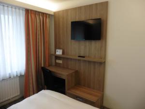 a hotel room with a desk and a television on a wall at Hotel Empire in Luxembourg