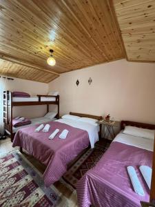 two beds in a room with wooden ceilings at Guest House Shtëpiza Theth in Theth