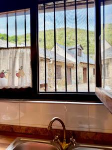 a kitchen window with a sink and a view of a building at CASA FOLIBAR-Encanto rural entre piedra y madera Valle del Silencio in Manzanedo de Valdueza +20 photos