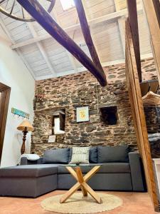a living room with a couch and a stone wall at CASA FOLIBAR-Encanto rural entre piedra y madera Valle del Silencio in Manzanedo de Valdueza
