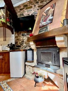 a kitchen with a stone fireplace and a refrigerator at CASA FOLIBAR-Encanto rural entre piedra y madera Valle del Silencio in Manzanedo de Valdueza
