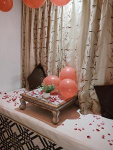 a bed with pink balloons and a table with hearts at hotel sargam sadan in Jāmb +55 photos