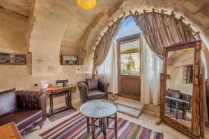 a living room with leather furniture and a large window at Cappa Via Cave Hotel in Ürgüp