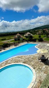 a large swimming pool with chairs and an umbrella at Flat em Gravatá - Villa Monte Castelo in Sairé