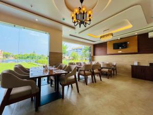 a dining room with tables and chairs and a chandelier at The Cristallo Resort in Shānti Niketan